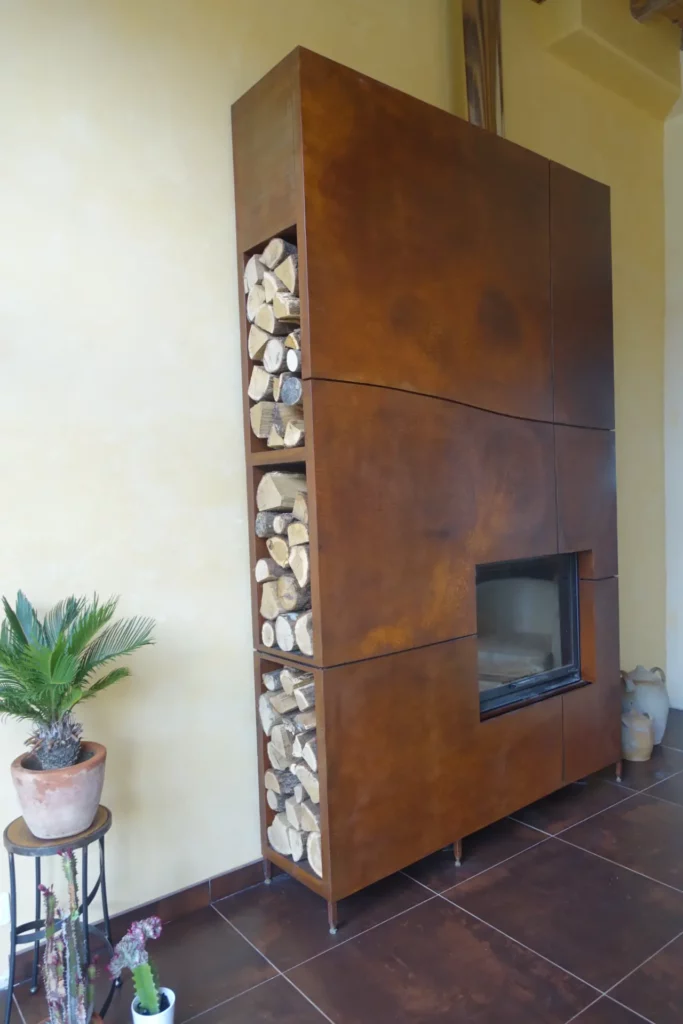 Habillage de cheminée insert en acier corten sur mesure avec niche à bûches intégrée en trois compartiments, finition oxydée naturelle rouille, réalisé par Christophe Barbarin ferronnier d'art Lyon Bourgogne